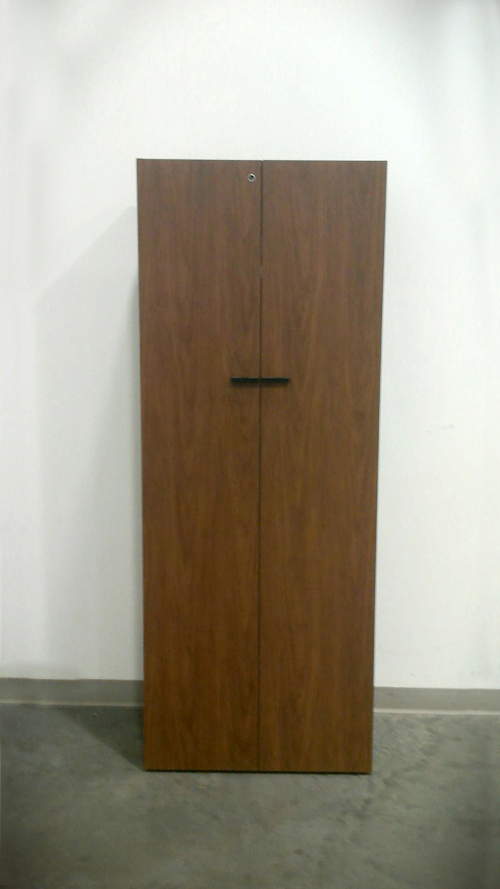 Freestanding Teknion wardrobe in rich walnut grain with black rectangular door pulls